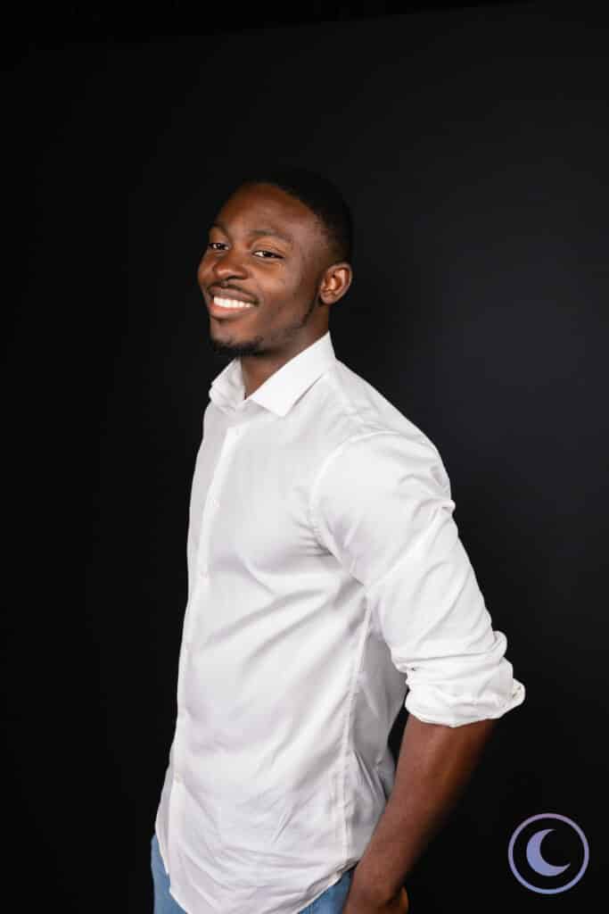 Professional studio portrait of man in white shirt smiling against dark backdrop with Luna Events logo