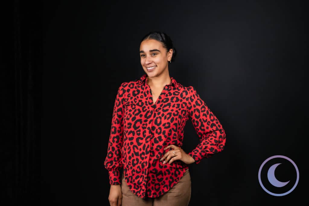 Professional woman posing confidently in red blouse on black background using Luna Events Headshot Booth